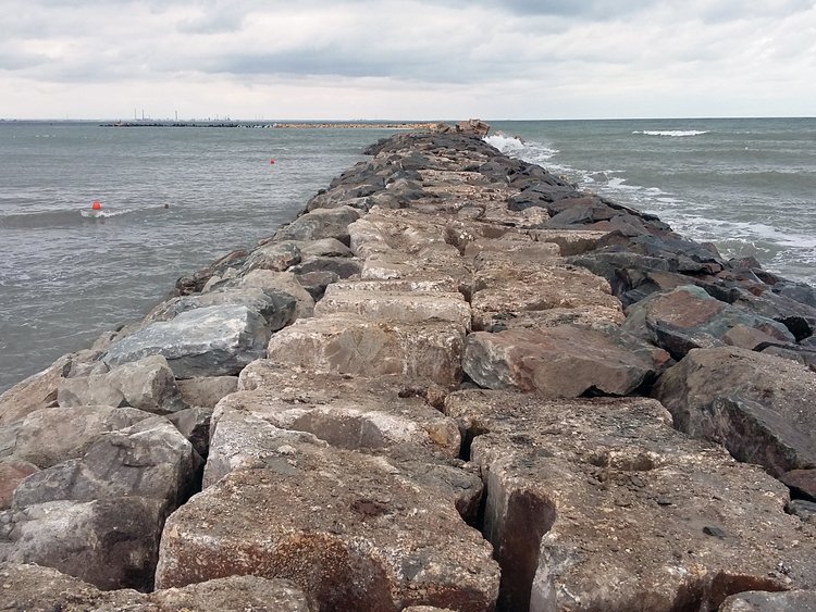 Photo: massive breakwater reaching out straight into the sea, gentle waves on both sides