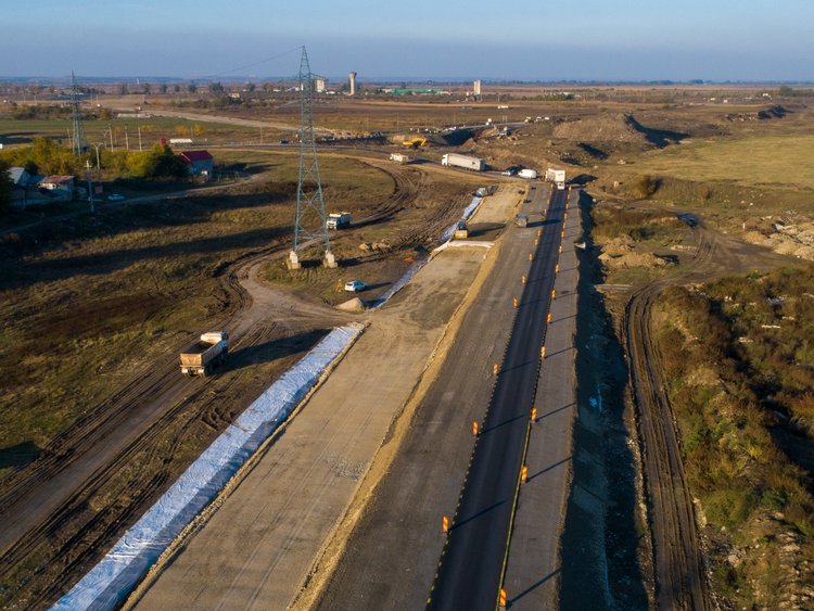 Fotografie aeriană: șosea dreaptă ce traversează o zonă rurală nedezvoltată în perspectiva punctului de fugă.