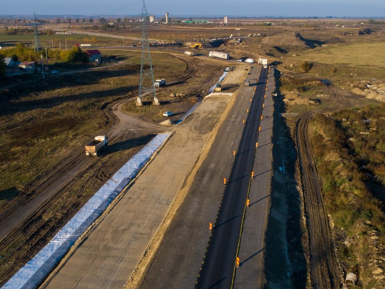 Aerial photo: very straight empty road construction site through undeveloped rural land in vanishing point perspective.